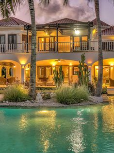 a large house with palm trees in front of it and a pool at the bottom