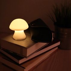 a mushroom lamp sitting on top of a stack of books next to a potted plant