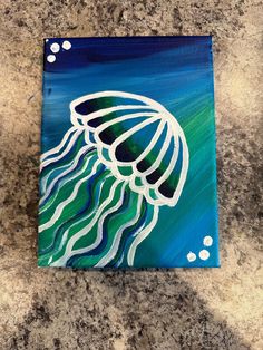 an acrylic painting of a jellyfish in blue and green on a granite countertop