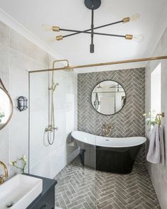 a bathroom with a black and white bathtub next to a sink under a round mirror