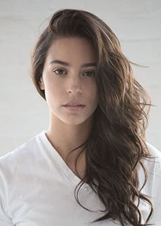 a woman with long brown hair wearing a white t - shirt and posing for the camera