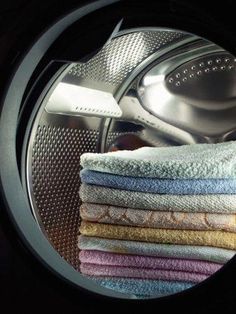 a stack of towels sitting inside of a dryer next to a pile of clothes