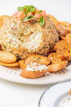 a white plate topped with crackers and a cheese ball covered in toppings on top of it