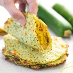 a person is dipping some food into a stack of crackers with cucumbers in the background