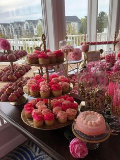 a table topped with lots of cupcakes covered in pink frosting