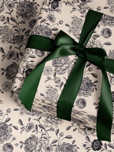 two wrapped presents with green ribbon on floral print wrapping paper, tied in a bow