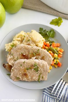 two slices of pork, mashed potatoes and carrots on a plate next to green apples