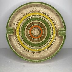 a green, yellow and orange bowl on a white surface with circles in the center