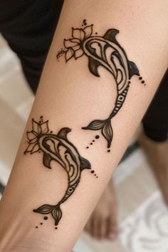 a woman's arm with two dolphins and flowers on the back of her arm