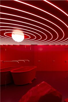 an empty room with red lighting in the ceiling and round lights on the walls above it