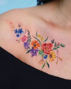 a woman's shoulder with colorful flowers on her left shoulder and the upper part of her chest