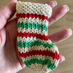 a hand holding a knitted mitt in the shape of a christmas stocking