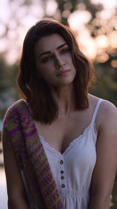 a woman with brown hair wearing a white top and scarf, posing for the camera