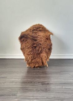 a brown chair sitting on top of a hard wood floor next to a white wall