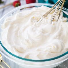 whipped cream in a glass bowl with two whisk attachments