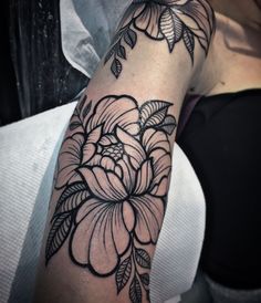 a black and white flower tattoo on the left arm, with leaves around it's edges