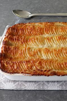 a casserole dish with potatoes in it and a spoon next to it on a napkin