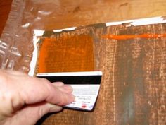 someone is painting wood with orange and brown paint