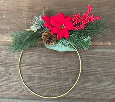 a headband with pine cones and poinsettis is on a wooden surface