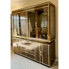 a large cabinet with glass doors and gold trimmings on the front, sitting in a living room