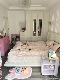 a bedroom with white furniture and pink accessories on the bed, nightstands and chest of drawers