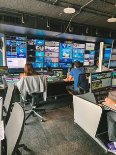 two people sitting at desks in front of multiple monitors