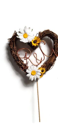 a heart shaped cake topper with daisies and the word love spelled on it