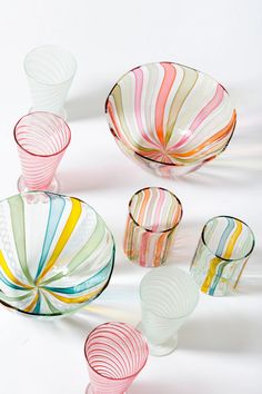 several colorful glass bowls and cups on a white surface