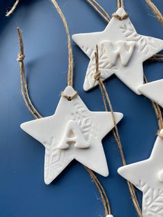 three white ceramic stars hanging from twine on a blue surface with rope and string