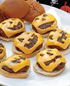 some hamburgers with cheese on them are sitting on a plate next to a stuffed animal