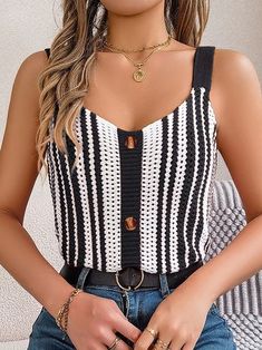 a woman wearing a black and white striped top holding a handbag in her right hand