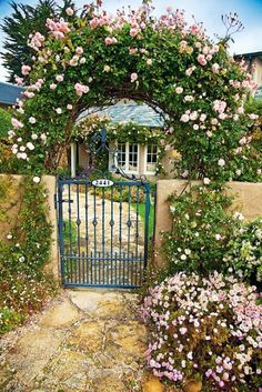 an iron gate surrounded by flowers and greenery