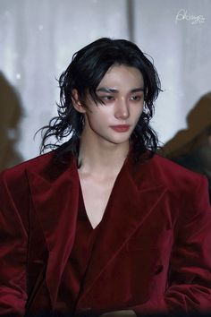 a woman with black hair wearing a red suit