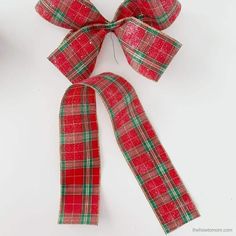 a red and green plaid ribbon tied to a white surface with scissors in the background