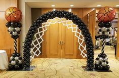 an arch made out of black and silver balloons with basketballs on it in the middle