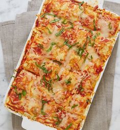 a casserole dish with cheese and vegetables in it sitting on a gray napkin