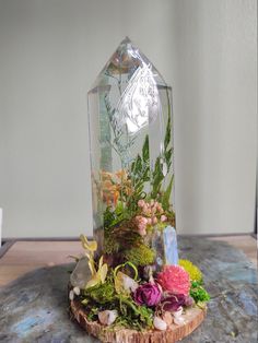 a glass vase filled with flowers and plants