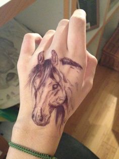 a person with a horse tattoo on their wrist and hand is shown in the photo