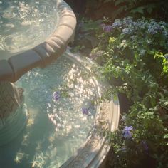 the fountain is surrounded by flowers and greenery