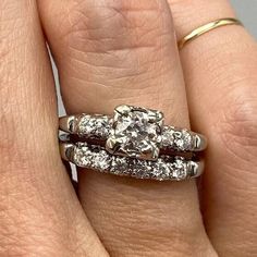 a woman's hand with two wedding rings on top of her finger and an engagement ring