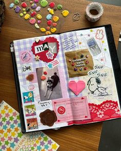 an open book on a table with buttons and other items around it, including candy