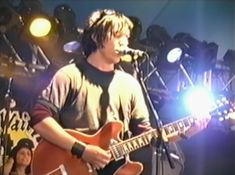 a young man with headphones on while playing an electric guitar in front of microphones