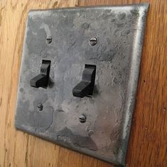 an electrical outlet cover with water drops on the wood floor and one light switch plate