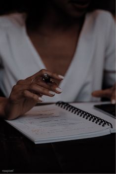 a woman sitting at a table with a notebook and pen in her hand