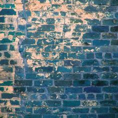 an old brick wall that has been painted blue and white with some green paint on it