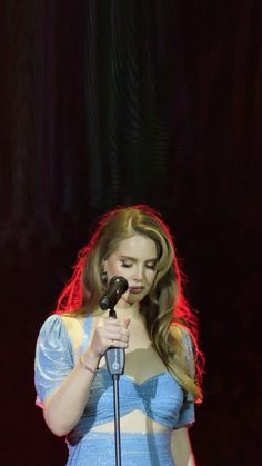 a woman standing in front of a microphone with her hand on top of the microphone