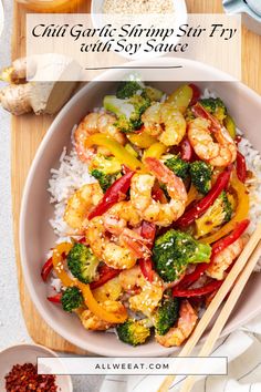 a bowl filled with shrimp, broccoli and peppers on top of rice next to chopsticks