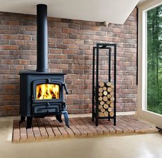 a wood burning stove next to a stack of logs