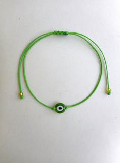 a green string bracelet with an evil eye charm