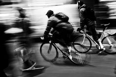 black and white photograph of bicyclists riding down the street